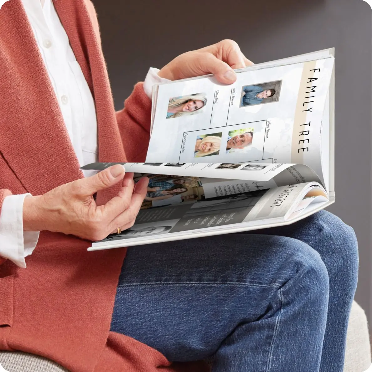A person in a red cardigan and blue jeans sitting and browsing through a photo book, with pages visible showing a variety of framed images and text captions, suggesting a personal or family album.