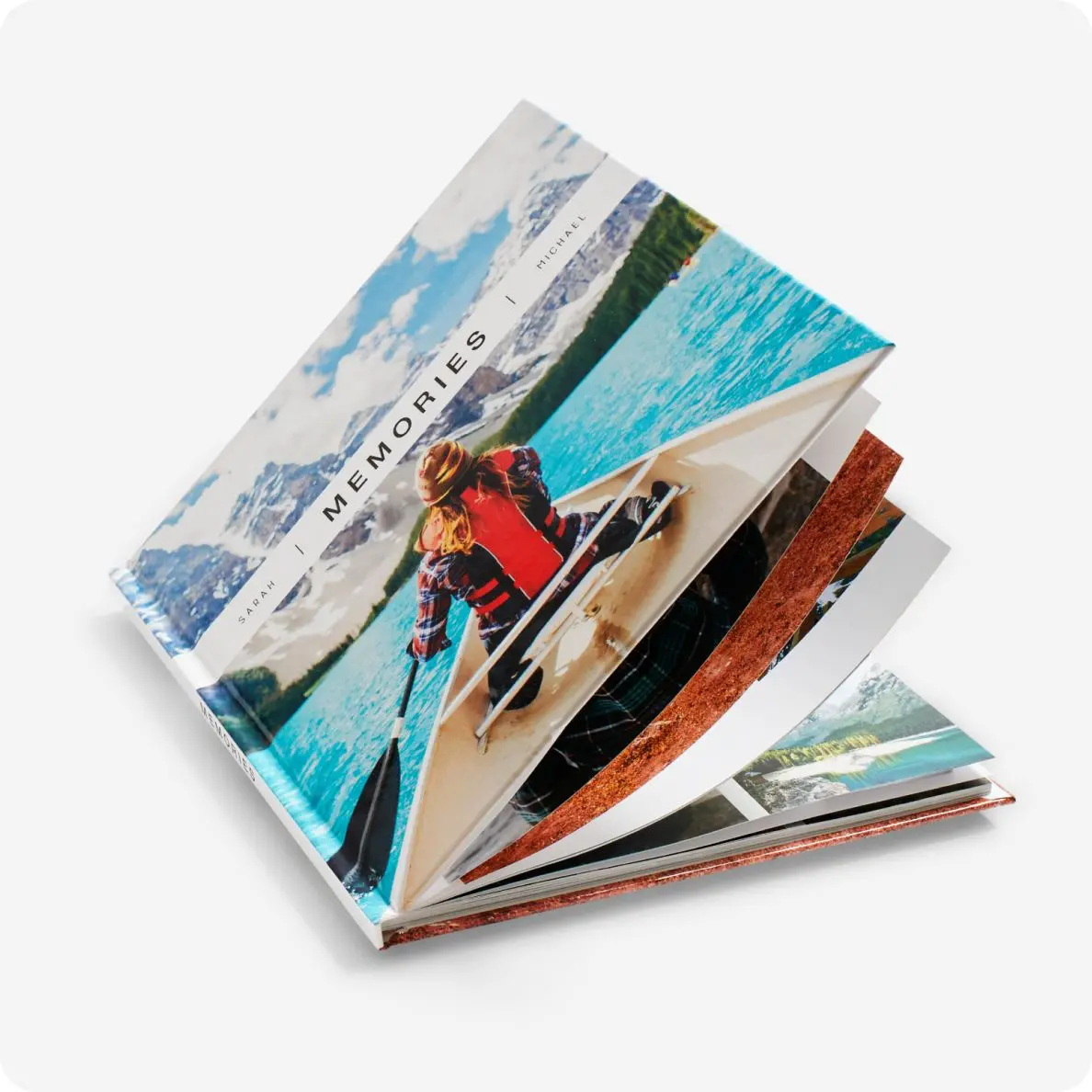 A photo book fanned open on a white background, displaying a collection of images including a person on a sailboat, showcasing moments of adventure and travel.